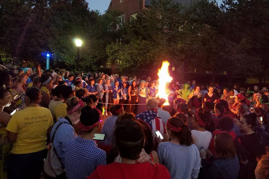 Dozens of students gather around a bonfire